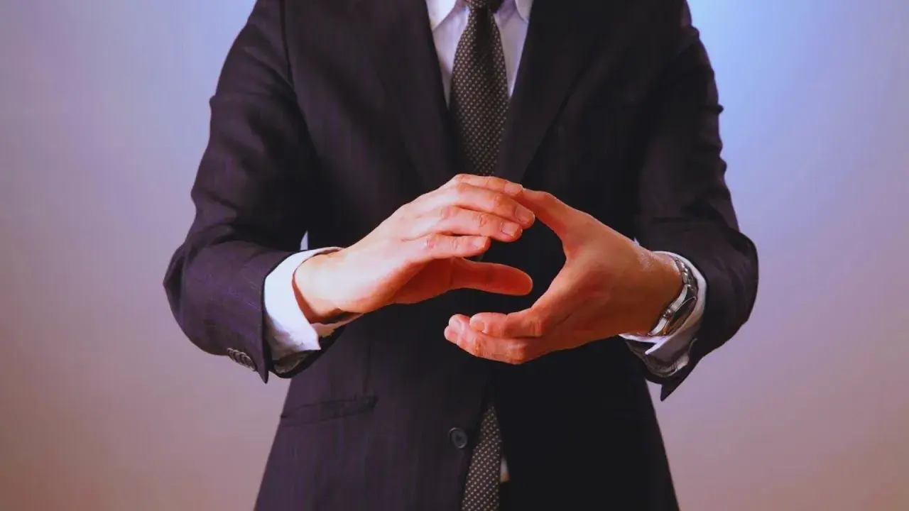 Manos entrelazadas en un gesto de **liderazgo ético**, vistiendo traje y corbata.