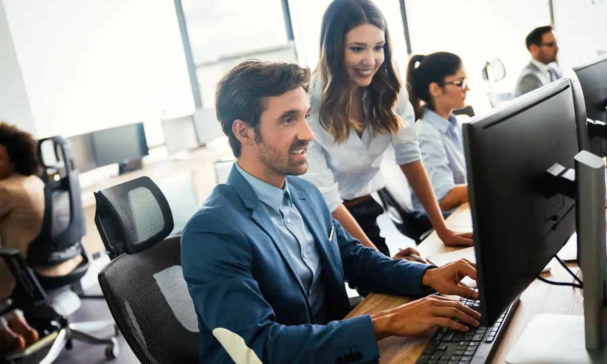 Un equipo colabora en la oficina, mostrando una excelente **comunicación en equipo** mientras trabajan en sus ordenadores.
