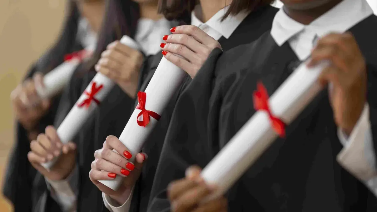 Graduados celebran el fin de su etapa para estudiar un MBA, sosteniendo sus diplomas con cintas rojas.