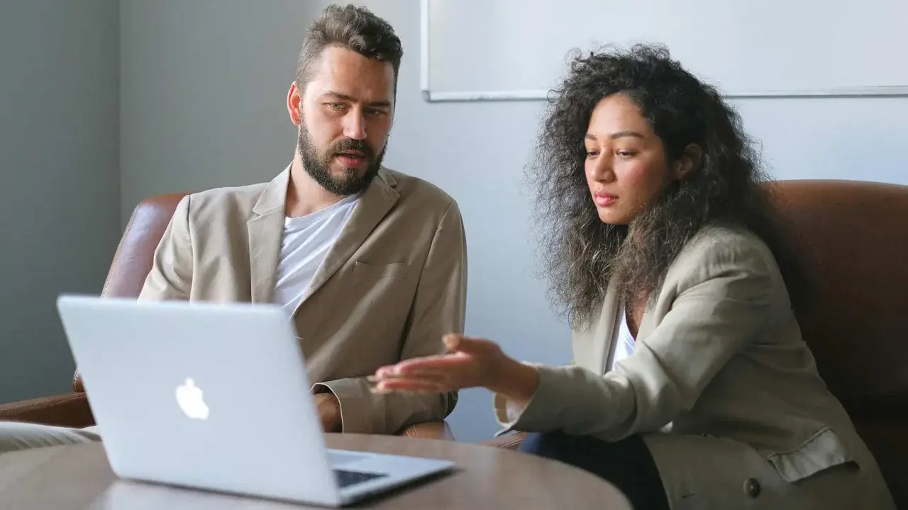 Un business developer y su colega analizan datos en una laptop.