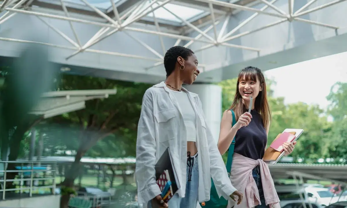 Dos estudiantes ríen mientras caminan, quizás planeando su próximo día de prácticas en España.