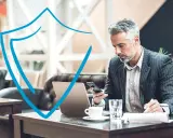 Hombre de negocios con portátil y móvil, trabajando en la nube con seguridad.