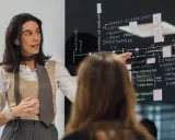 Mujer explica un diagrama en pizarra, parte de un programa de desarrollo de gestión.