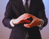 Manos entrelazadas en un gesto de **liderazgo ético**, vistiendo traje y corbata.