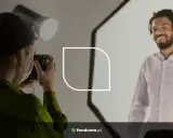 Fotógrafa toma fotos para CV de un hombre sonriente.