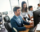 Un equipo colabora en la oficina, mostrando una excelente **comunicación en equipo** mientras trabajan en sus ordenadores.