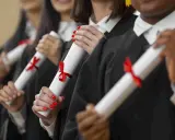 Graduados celebran el fin de su etapa para estudiar un MBA, sosteniendo sus diplomas con cintas rojas.