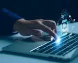 Dedo sobre teclado de laptop interactuando con un chip digital que muestra "Fin Tech" y varios iconos financieros, simbolizando el desarrollo de software fintech.