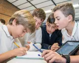 Chicos colaboran en un proyecto, usando tablet y cuaderno. Sus metodologías de aprendizaje son variadas y efectivas.