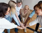 Un equipo diverso celebra el éxito con un apretón de manos, demostrando el poder del liderazgo participativo y la colaboración.