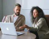 Un business developer y su colega analizan datos en una laptop.