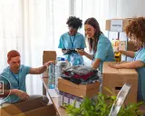 Voluntarios organizan donaciones. Un hombre revisa una lista, mientras otros empaquetan ropa y agua. Su cv volunteering es valioso.