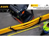 Carretilla elevadora junto a barreras amarillas de seguridad A-SAFE, mejorando la circulación en ntp lugares de trabajo. Un trabajador con chaleco reflectante camina cerca.