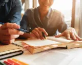 Estudiantes revisan apuntes y libros, preparándose para obtener becas MBA.