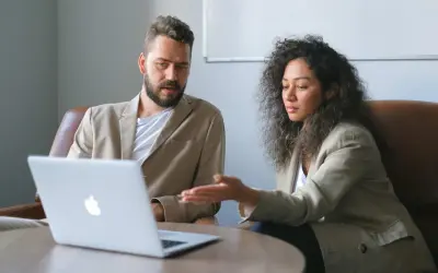 Un business developer y su colega analizan datos en una laptop.