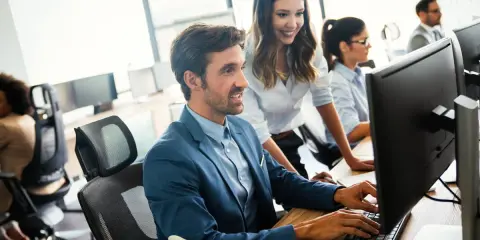 Un equipo colabora en la oficina, mostrando una excelente **comunicación en equipo** mientras trabajan en sus ordenadores.