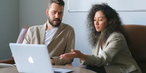 Un business developer y su colega analizan datos en una laptop.