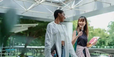 Dos estudiantes ríen mientras caminan, quizás planeando su próximo día de prácticas en España.