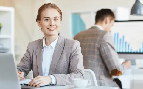 Mujer sonríe mientras se prepara para una entrevista de trabajo, tomando notas en su portátil.