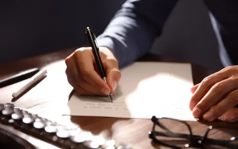Mano escribiendo una carta formal con bolígrafo.