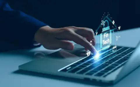 Dedo sobre teclado de laptop interactuando con un chip digital que muestra "Fin Tech" y varios iconos financieros, simbolizando el desarrollo de software fintech.