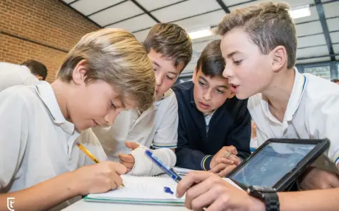 Chicos colaboran en un proyecto, usando tablet y cuaderno. Sus metodologías de aprendizaje son variadas y efectivas.