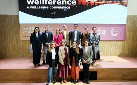 Grupo posa en el escenario de la conferencia "wellference", con el logo de ntp 639 visible.