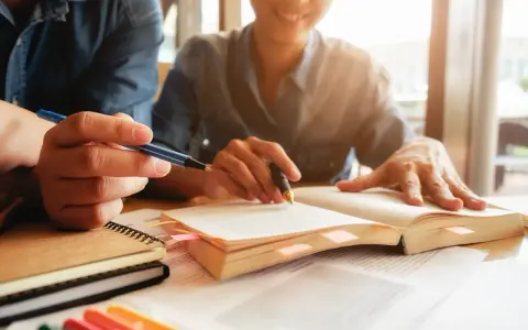 Estudiantes revisan apuntes y libros, preparándose para obtener becas MBA.