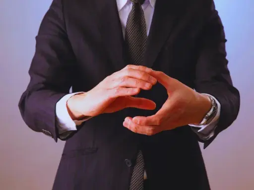 Manos entrelazadas en un gesto de **liderazgo ético**, vistiendo traje y corbata.