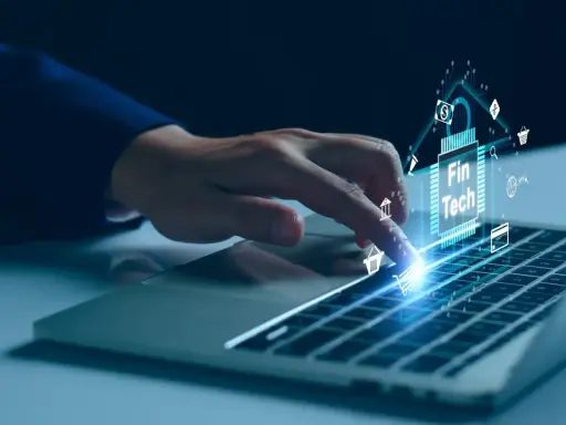 Dedo sobre teclado de laptop interactuando con un chip digital que muestra "Fin Tech" y varios iconos financieros, simbolizando el desarrollo de software fintech.