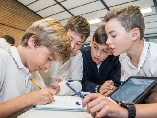 Chicos colaboran en un proyecto, usando tablet y cuaderno. Sus metodologías de aprendizaje son variadas y efectivas.