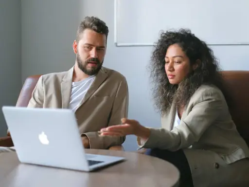 Un business developer y su colega analizan datos en una laptop.