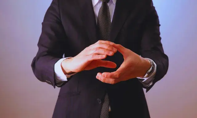 Manos entrelazadas en un gesto de **liderazgo ético**, vistiendo traje y corbata.