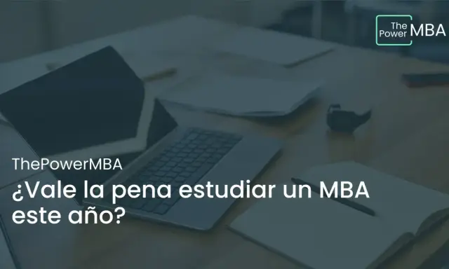 Un portátil y un cuaderno abierto sobre un escritorio, con el texto "¿Vale la pena estudiar un MBA este año?".