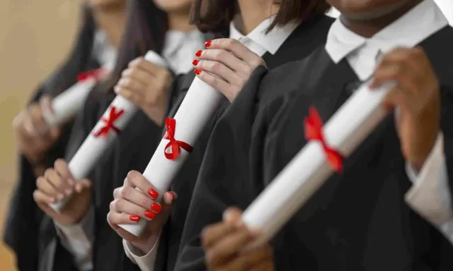 Graduados celebran el fin de su etapa para estudiar un MBA, sosteniendo sus diplomas con cintas rojas.