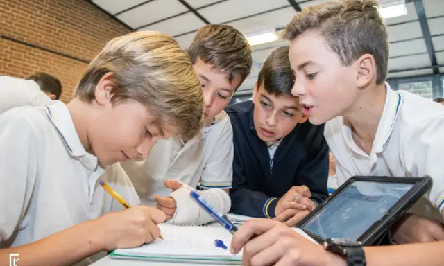 Chicos colaboran en un proyecto, usando tablet y cuaderno. Sus metodologías de aprendizaje son variadas y efectivas.