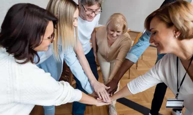 Un equipo diverso celebra el éxito con un apretón de manos, demostrando el poder del liderazgo participativo y la colaboración.