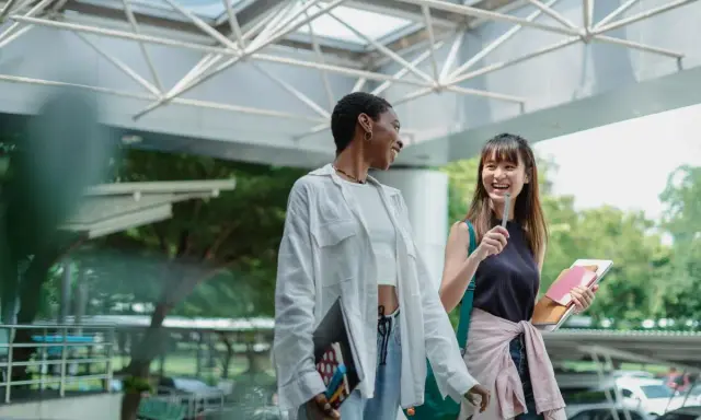 Dos estudiantes ríen mientras caminan, quizás planeando su próximo día de prácticas en España.