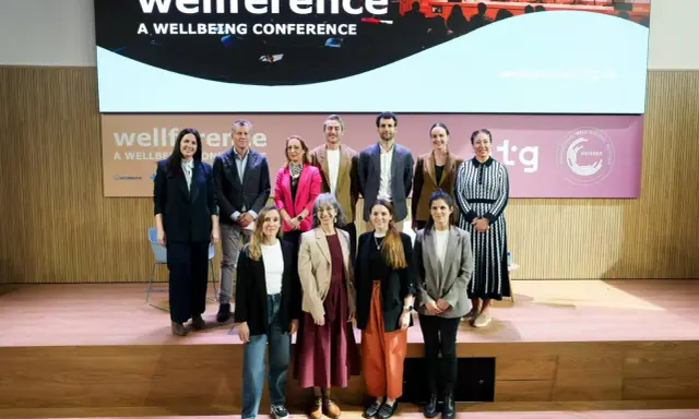 Grupo posa en el escenario de la conferencia "wellference", con el logo de ntp 639 visible.