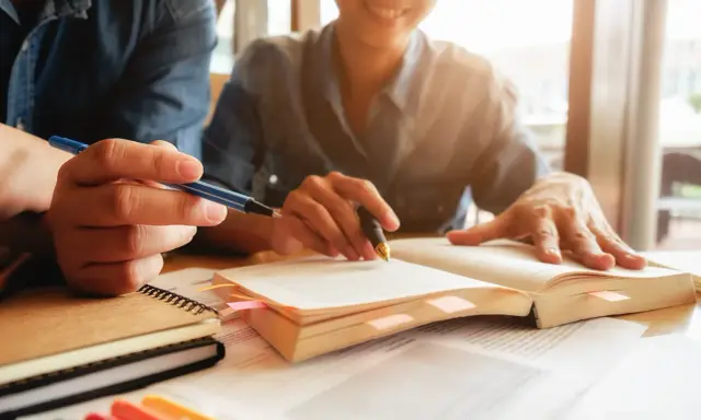 Estudiantes revisan apuntes y libros, preparándose para obtener becas MBA.