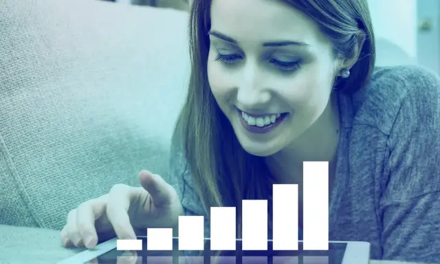 Mujer sonríe mientras interactúa con una tablet que muestra un gráfico de barras ascendente, simbolizando el liderazgo transformacional y el crecimiento.
