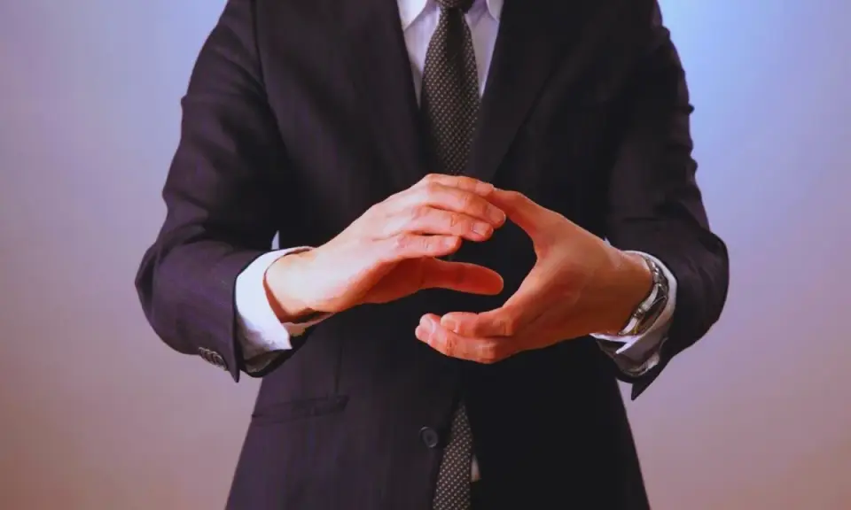 Manos entrelazadas en un gesto de **liderazgo ético**, vistiendo traje y corbata.