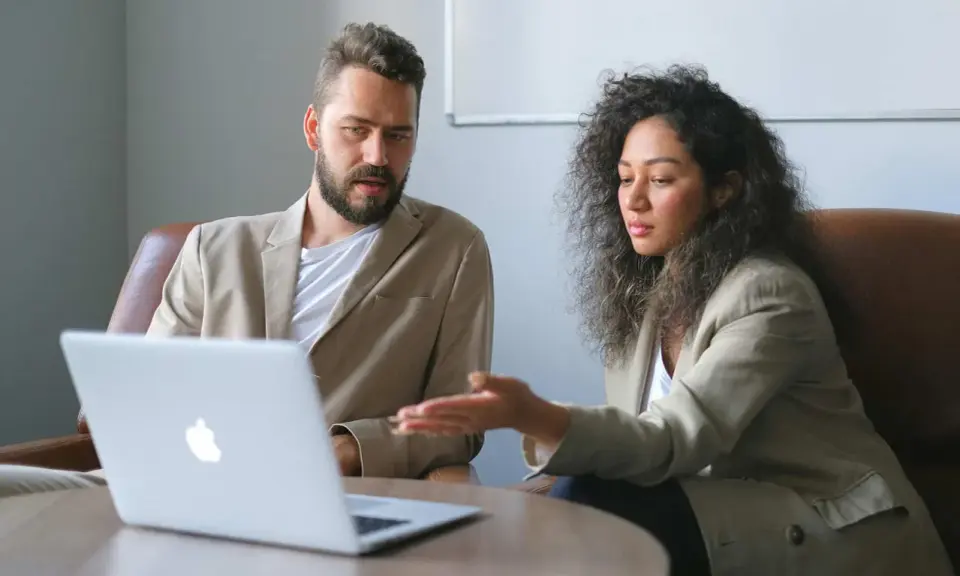 Un business developer y su colega analizan datos en una laptop.