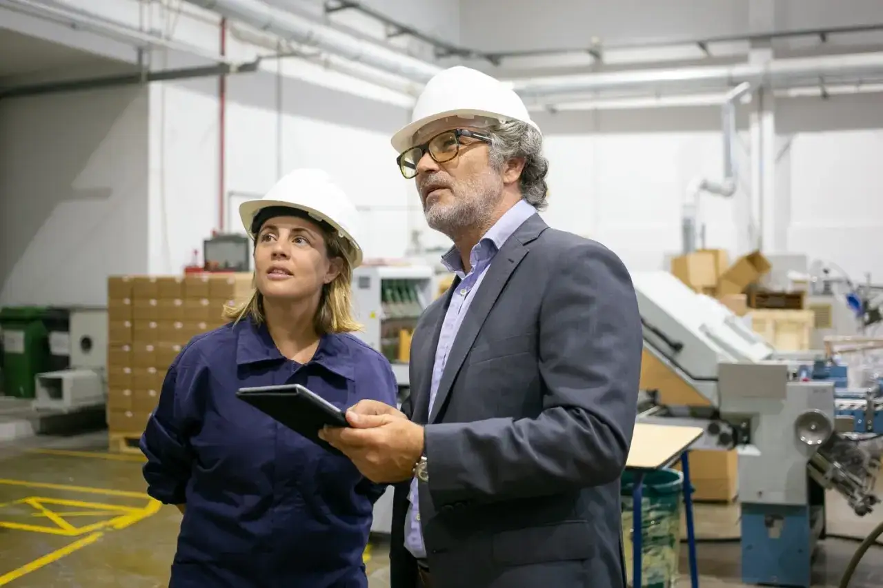 Supervisor de producci&oacute;n y su colega revisan el proceso en una f&aacute;brica.