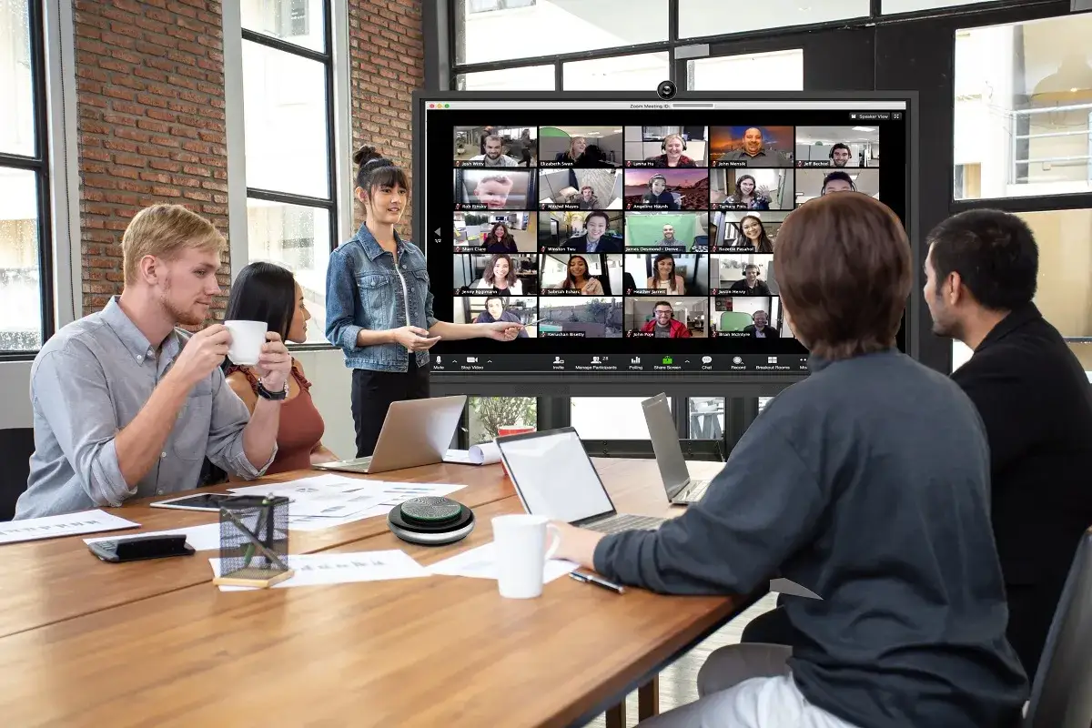 Equipo en reuni&oacute;n virtual, una mujer presenta en pantalla dividida. Quiz&aacute;s est&eacute;n usando preguntas para romper el hielo.