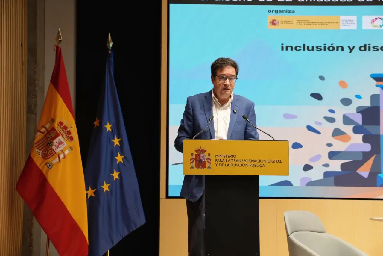 Ponente habla sobre gestión pública, con banderas de España y UE.