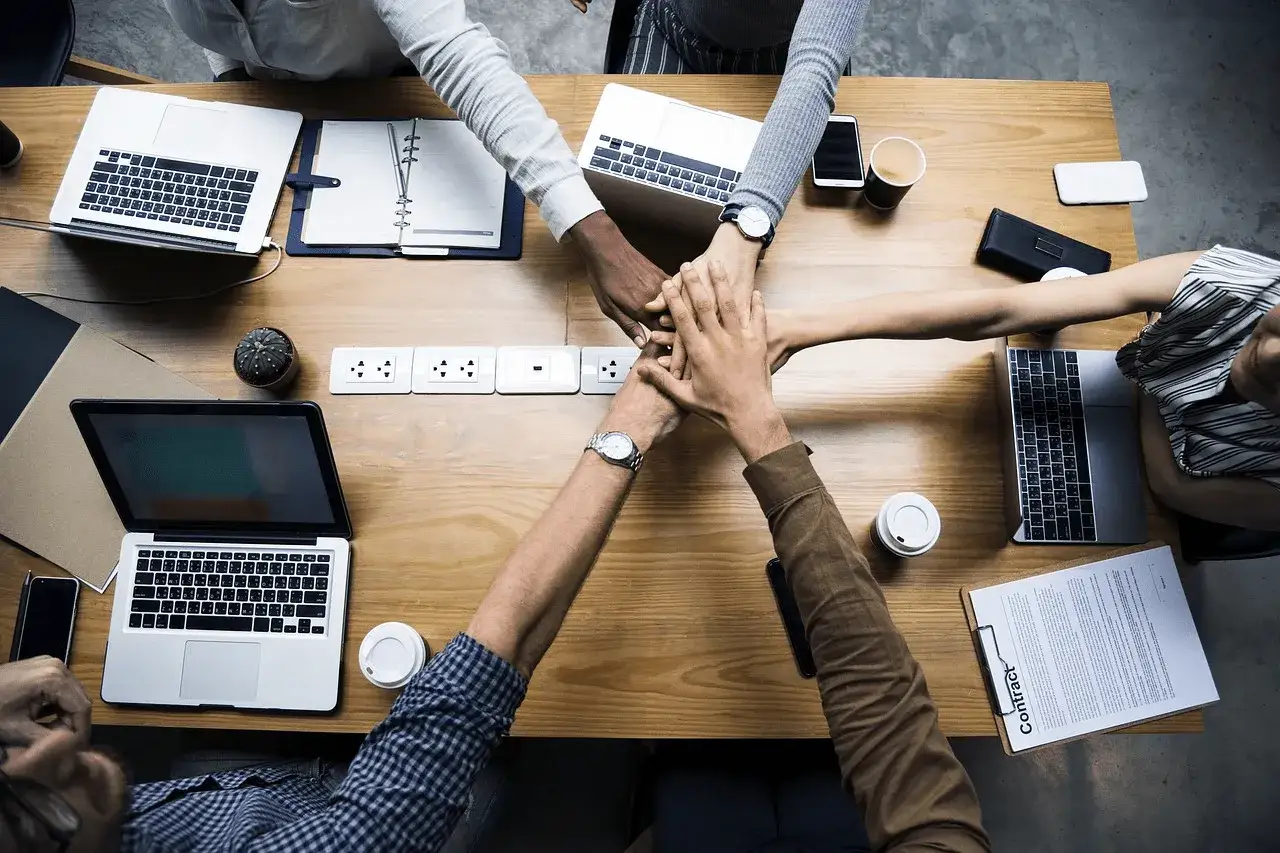 Manos unidas en equipo, reflejo del esfuerzo y la colaboraci&oacute;n en la middle management para alcanzar metas.