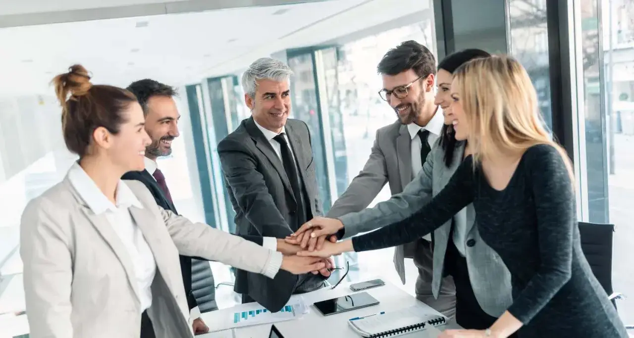 Equipo unido, manos entrelazadas, un ejemplo de cómo mejorar la comunicación interna de una empresa.