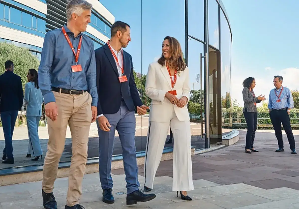 Profesionales con credenciales pdg iese caminan y conversan frente a un edificio moderno.