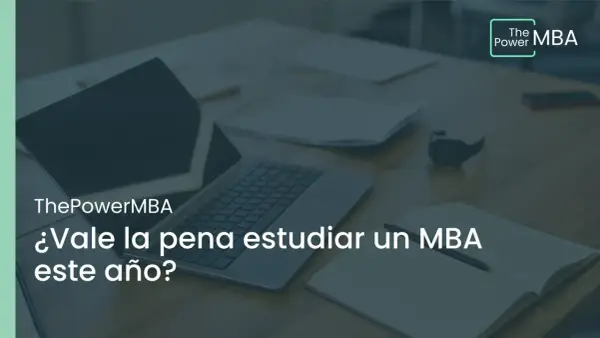 Un portátil y un cuaderno abierto sobre un escritorio, con el texto "¿Vale la pena estudiar un MBA este año?".